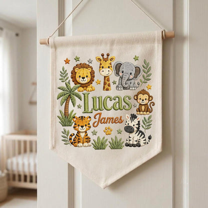 May include: A cream-colored fabric wall hanging banner featuring a colorful illustration of a lion, giraffe, elephant, monkey, tiger, and zebra. The text Lucas James is printed in the center in green and orange script surrounded by small stars.