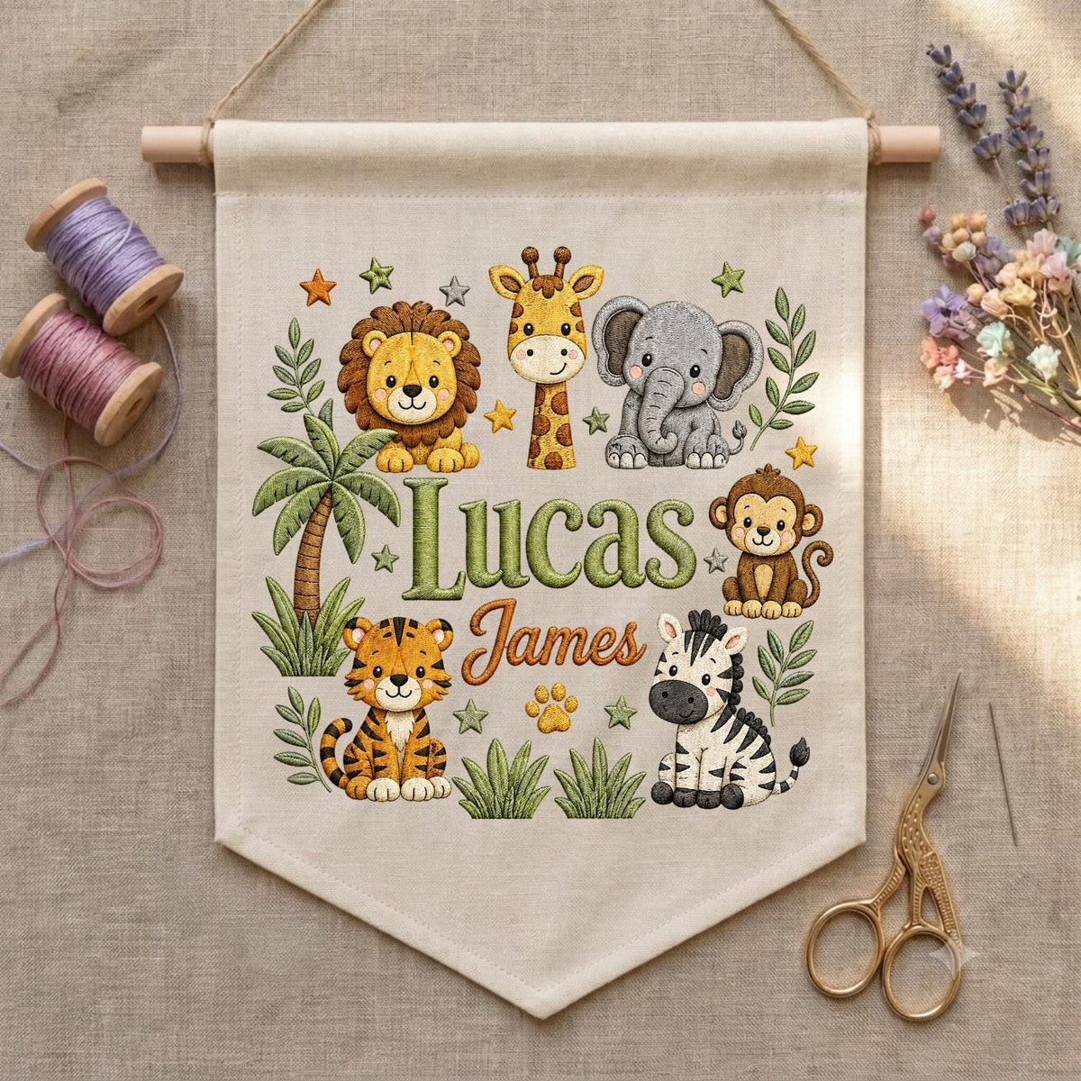 May include: A beige fabric wall hanging featuring a printed jungle theme with a lion, giraffe, elephant, monkey, tiger, and zebra. The text reads Lucas James in green and orange script. The banner is suspended from a wooden dowel with twine.