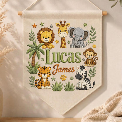 May include: A cream-colored fabric wall banner featuring embroidered illustrations of a lion, giraffe, elephant, monkey, tiger, and zebra. The text Lucas James is centered in green and orange script. The design includes palm trees and stars.