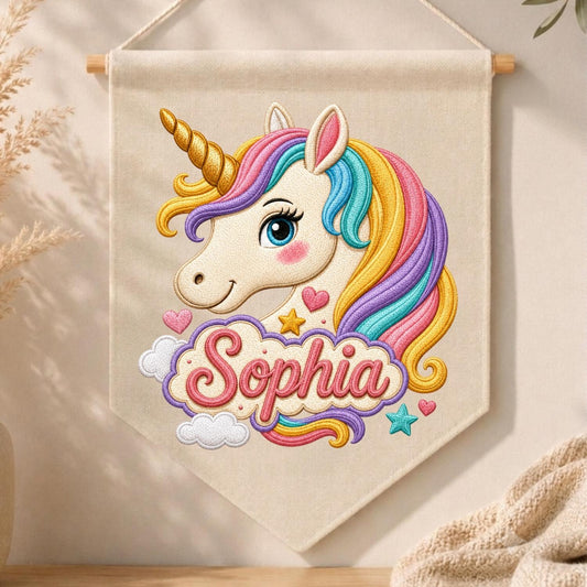 May include: A cream-colored fabric wall banner featuring an embroidered unicorn head with a gold horn and a multi-colored mane in pink, yellow, blue, and purple. Below the unicorn, the name Sophia is embroidered in pink script on a cloud.