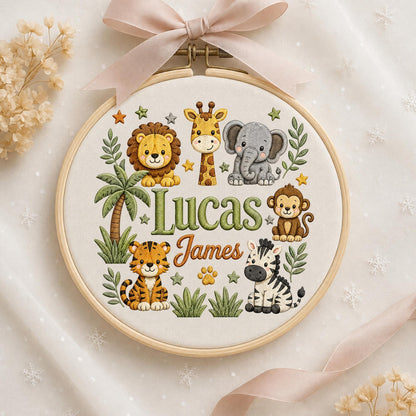 May include: A circular wooden embroidery hoop containing fabric with a stitched design of a lion, giraffe, elephant, monkey, tiger, and zebra. The text "Lucas James" is embroidered in the center, surrounded by palm trees, leaves, and stars.