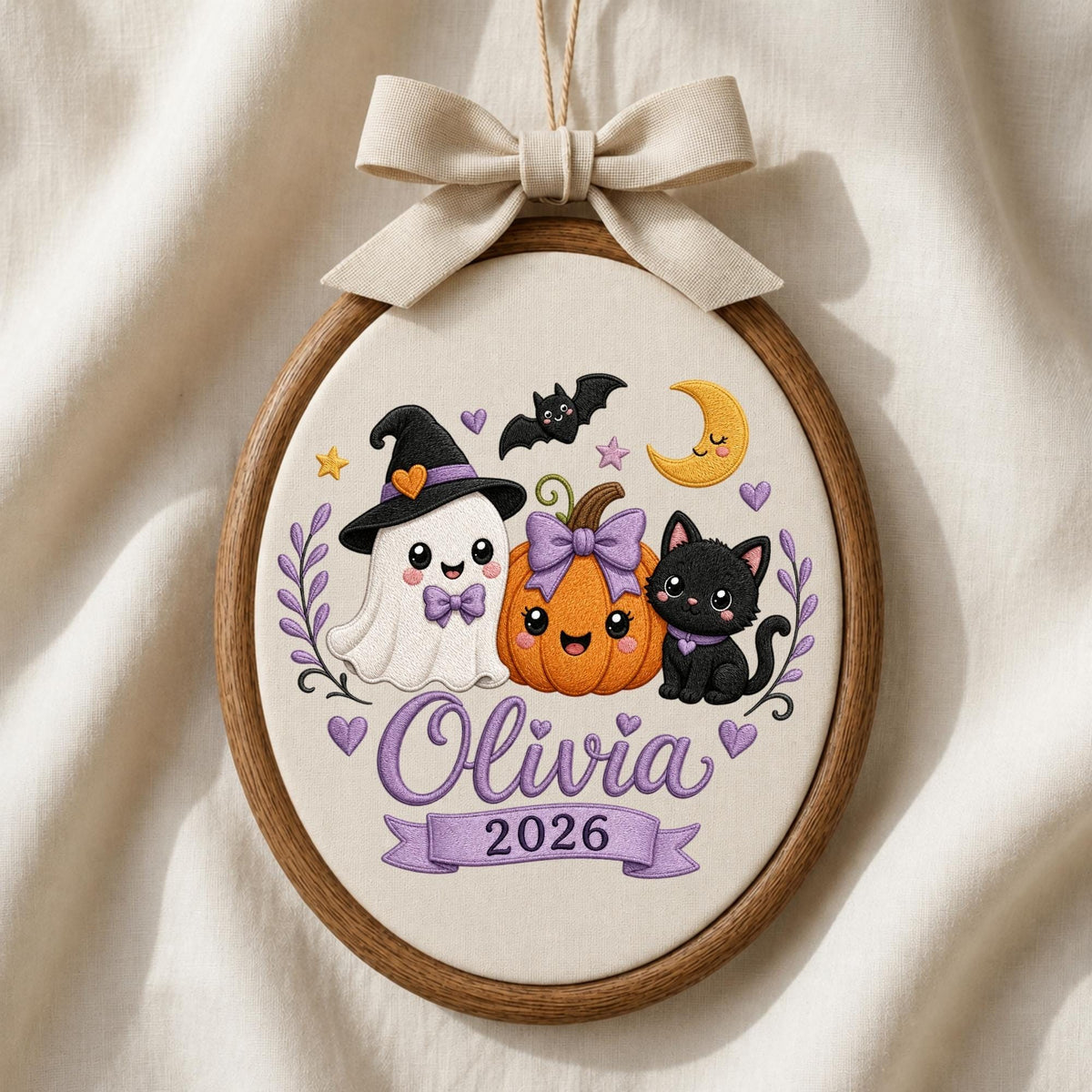 May include: An oval embroidery hoop featuring a white fabric background with a ghost wearing a witch hat, a pumpkin with a purple bow, and a black cat. The design includes a yellow crescent moon, stars, hearts, and the text Olivia 2026.