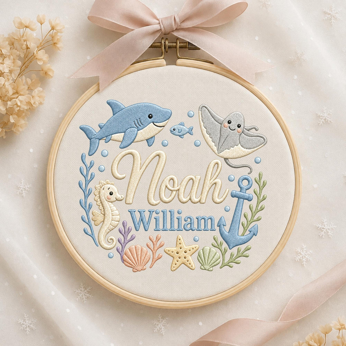 May include: A round wooden embroidery hoop containing fabric with a stitched ocean theme. The design features a blue shark, a stingray, a seahorse, a starfish, seashells, and an anchor. The names Noah and William are embroidered in the center.