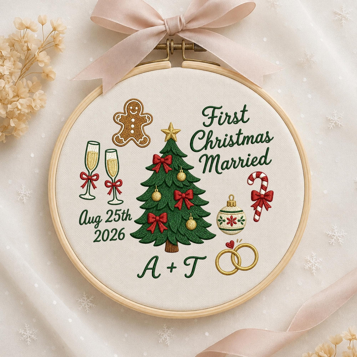 May include: A round wooden embroidery hoop containing white fabric with embroidered designs including a green Christmas tree, a gingerbread man, two champagne flutes, a candy cane, and two gold rings. Text reads First Christmas Married Aug 25th 2026 A + T.