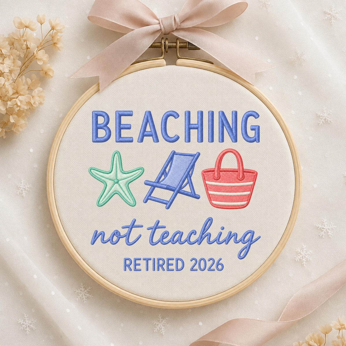May include: A circular embroidery hoop containing off-white fabric with the blue embroidered text BEACHING not teaching and RETIRED 2026. Between the text are a light green starfish, a blue beach chair, and a red and white striped beach bag.