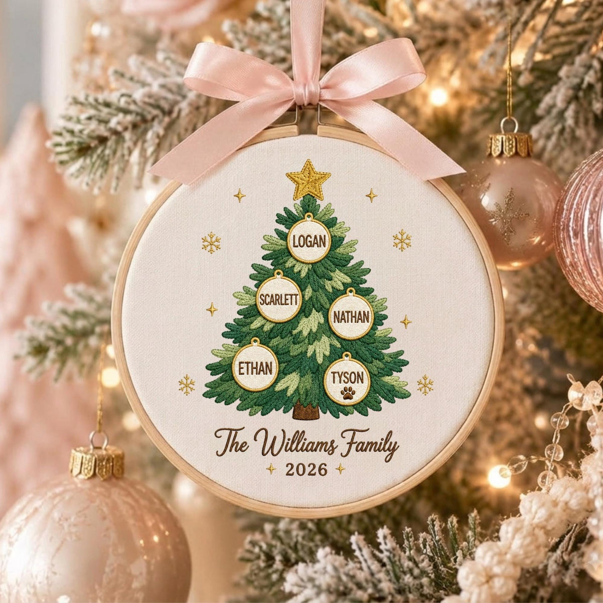 May include: A round wooden embroidery hoop ornament featuring a stitched green Christmas tree with a gold star. The tree displays five white circular ornaments with the names Logan, Scarlett, Nathan, Ethan, and Tyson. Text reads The Williams Family 2026.
