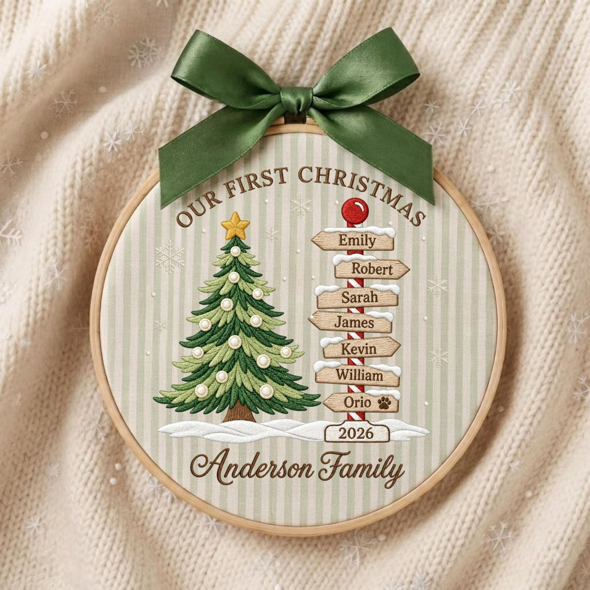 May include: A round wooden embroidery hoop ornament featuring a green Christmas tree with white ornaments and a signpost with the names Emily, Robert, Sarah, James, Kevin, William, Orio, and the text Our First Christmas Anderson Family 2026.