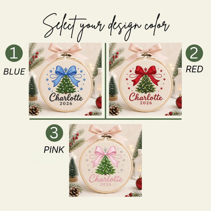May include: Three circular embroidery hoops featuring a Christmas tree design with a bow, the name Charlotte, and the year 2026. The options include a blue bow, a red bow, and a pink bow, each topped with a light pink ribbon for hanging.