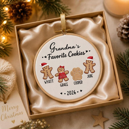 May include: A round embroidery hoop ornament featuring the embroidered text Grandma's Favorite Cookies, four gingerbread figures including a paw print, and the names Wyatt, Grace, Cooper, and Jude, with the year 2026, all in a gift box.