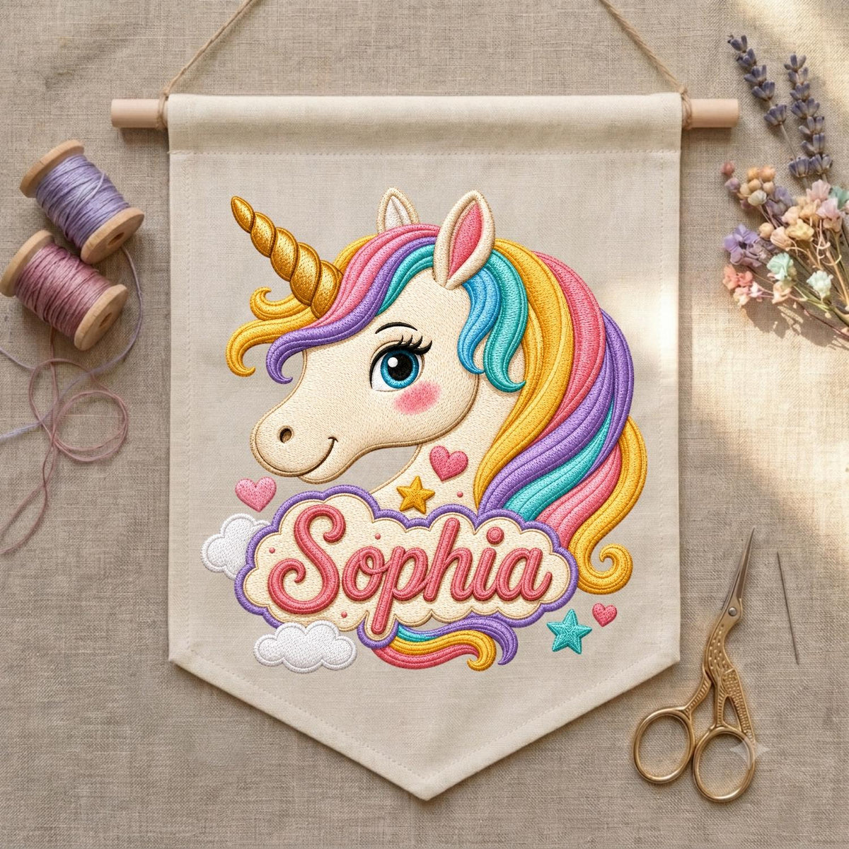 May include: A beige fabric wall banner featuring an embroidered unicorn with a gold horn and a multi-colored mane in shades of pink, yellow, and blue. Below the unicorn, the name Sophia is embroidered in pink script within a cloud-shaped border.