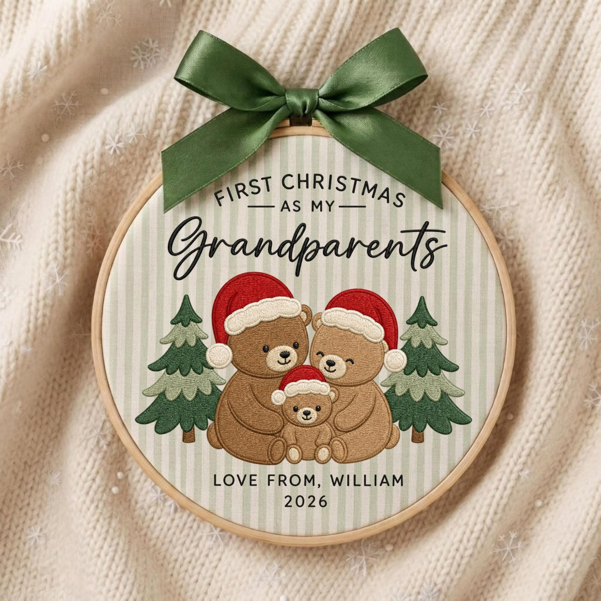 May include: A round embroidery hoop ornament featuring a light green striped fabric with a dark green satin bow at the top. The text reads First Christmas as my Grandparents, Love from, William, 2026, with three brown teddy bears in Santa hats.