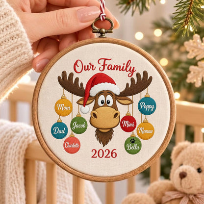 May include: A round wooden embroidery hoop ornament featuring a tan moose wearing a red and white Santa hat. The text Our Family and 2026 are embroidered in red. Eight colorful ornaments hang from the moose antlers with names Mom, Dad, Charlotte, Jacob, Mimi, Memaw, Poppy, and Bella.