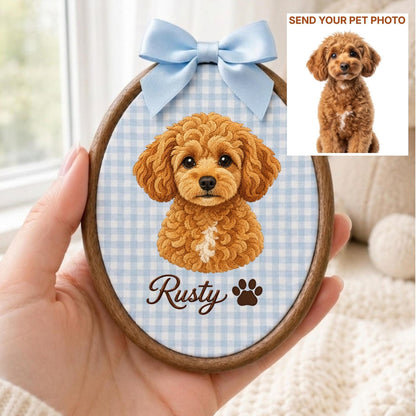 May include: An oval wooden embroidery hoop frame containing a light blue and white gingham fabric background. The fabric features a brown curly-haired dog illustration, the name Rusty in brown script, a brown paw print, and a light blue satin bow.