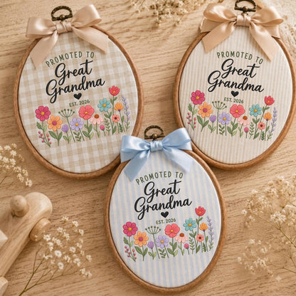 May include: Three oval wooden embroidery hoops featuring fabric backgrounds with gingham, vertical stripe, and pinstripe patterns. Each hoop displays the text "PROMOTED TO Great Grandma EST. 2026" above a colorful floral illustration and a satin bow.