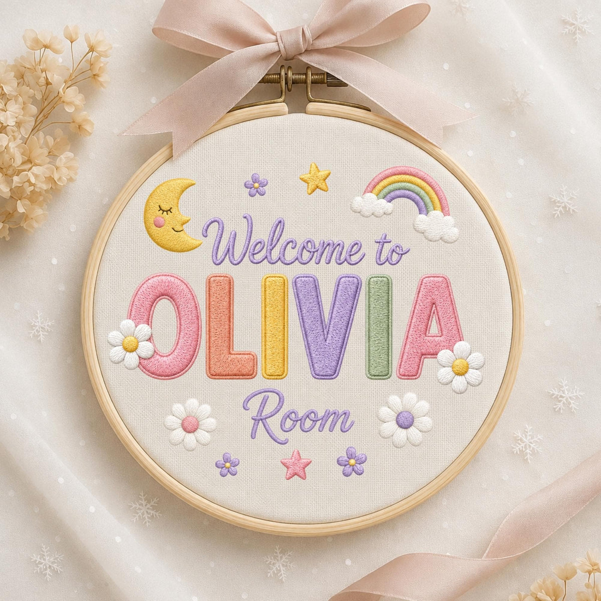May include: A circular wooden embroidery hoop containing white fabric with the embroidered text Welcome to OLIVIA Room. The design features a yellow crescent moon, a colorful rainbow, stars, and white daisies. A light pink ribbon is tied at the top.
