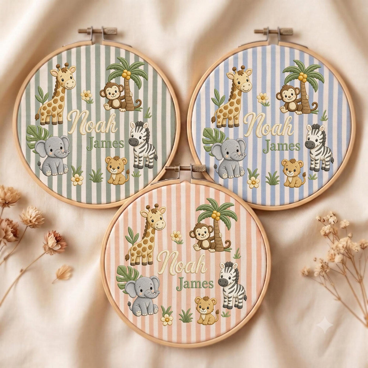 May include: Three circular wooden embroidery hoops featuring fabric with vertical stripes in sage green, light blue, and peach. Each hoop displays embroidered cartoon animals including a giraffe, monkey, elephant, zebra, and lion with the name Noah James.