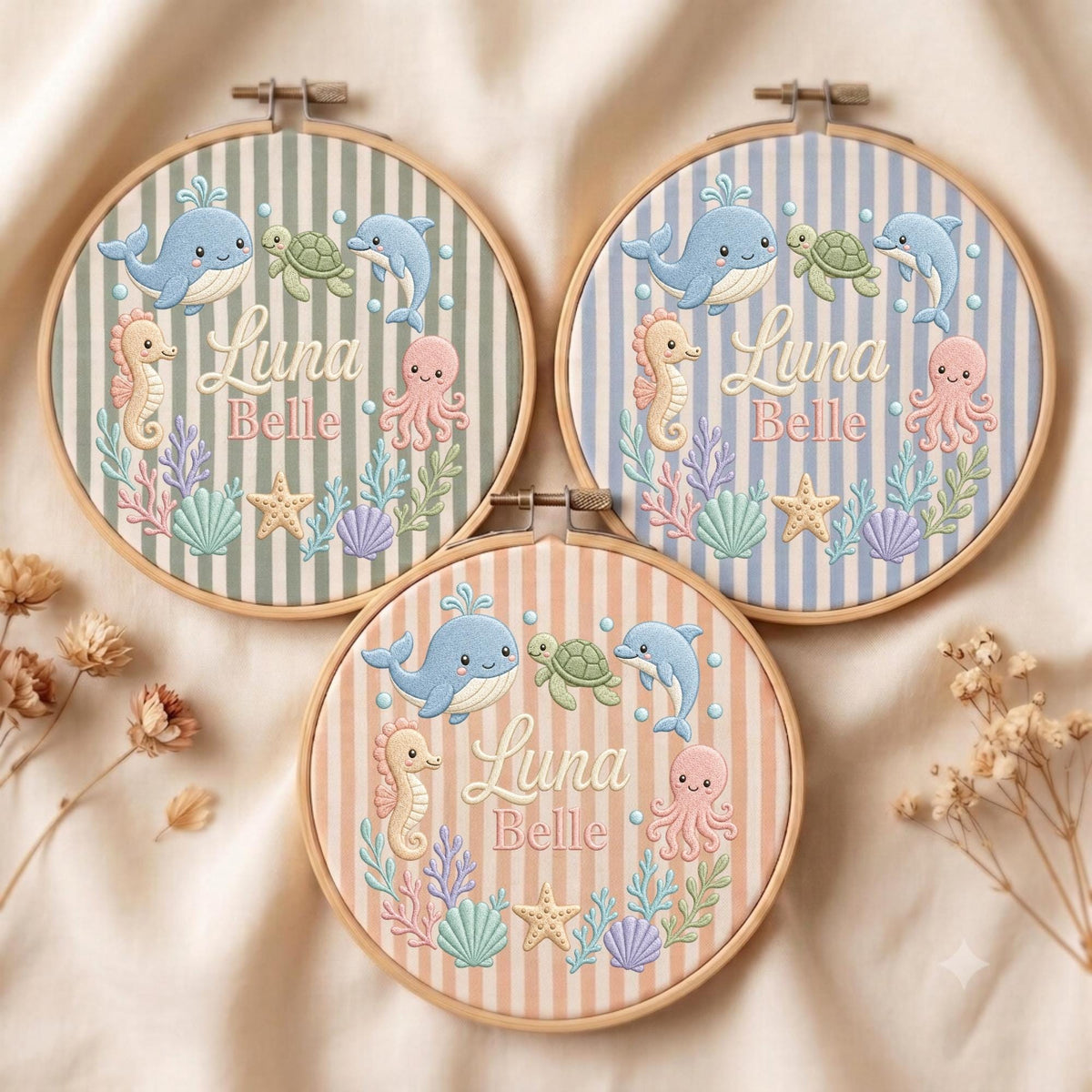May include: Three circular wooden embroidery hoops featuring striped fabric backgrounds in sage green, light blue, and peach. Each hoop displays embroidered sea creatures including a whale, turtle, dolphin, seahorse, and octopus, with the text Luna Belle.