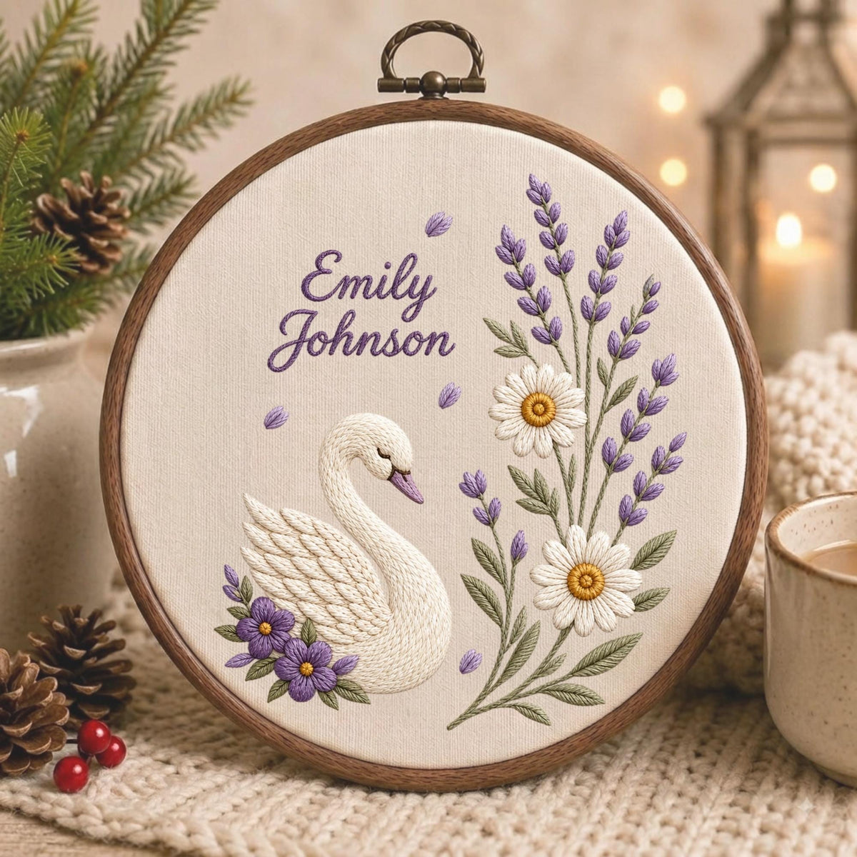 May include: A circular wooden embroidery hoop containing a cream-colored fabric panel. The embroidery features a white swan, purple lavender sprigs, and two white daisies with yellow centers. The text Emily Johnson is stitched in purple thread.