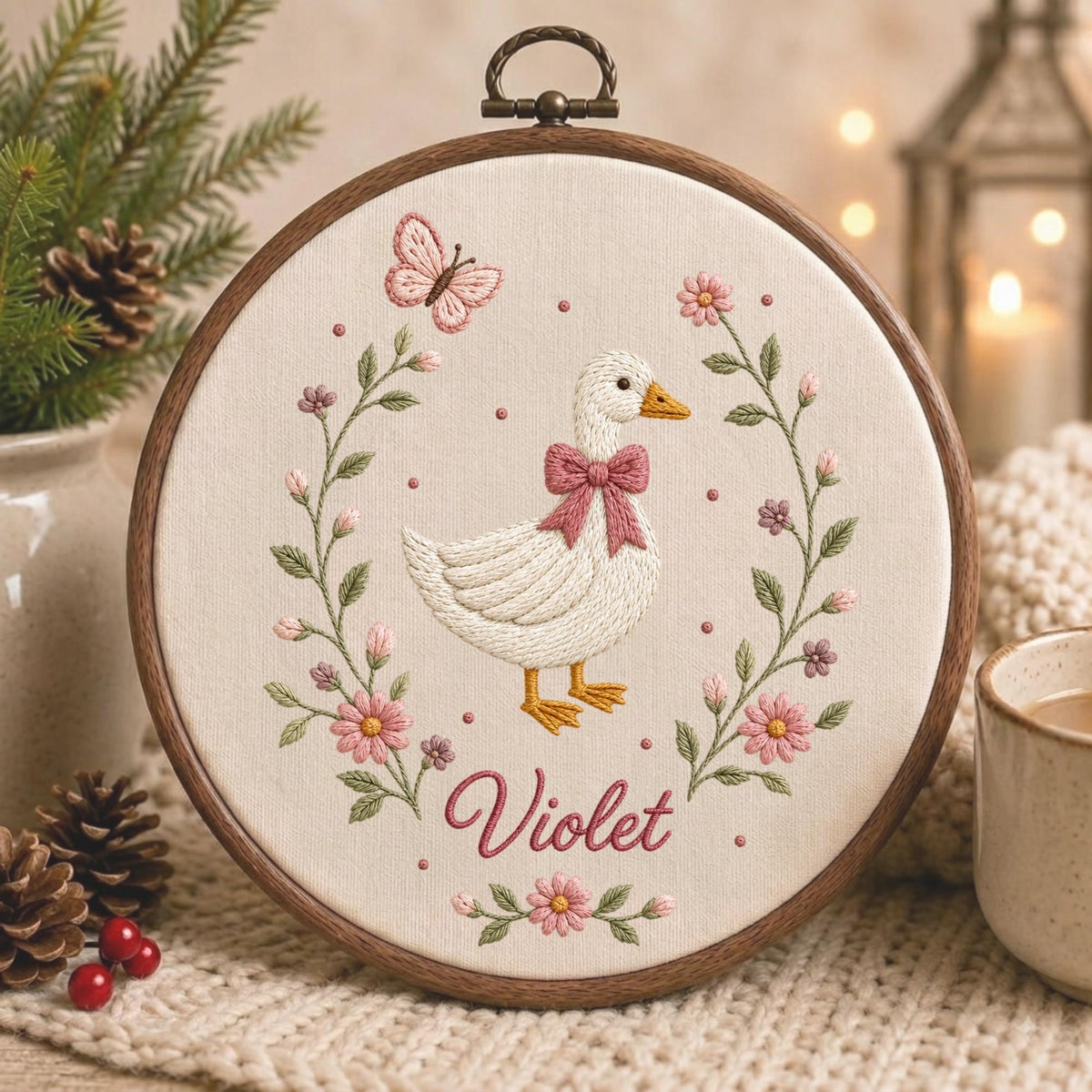 May include: A circular wooden embroidery hoop containing a cream-colored fabric panel. The embroidery features a white duck with a pink bow, surrounded by a floral wreath of pink flowers, green leaves, and a butterfly, with the name Violet below.