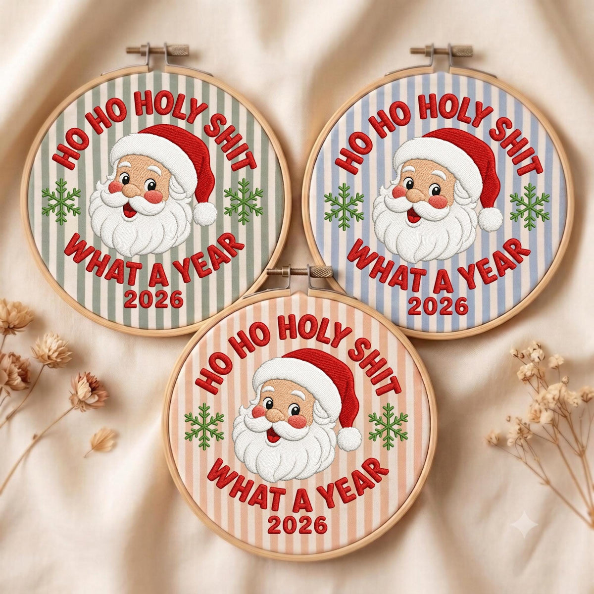May include: Three circular embroidery hoops featuring a cartoon Santa Claus face, green snowflakes, and the red embroidered text HO HO HOLY SHIT WHAT A YEAR 2026. The fabric backgrounds are striped in light green, light blue, and light peach colors.