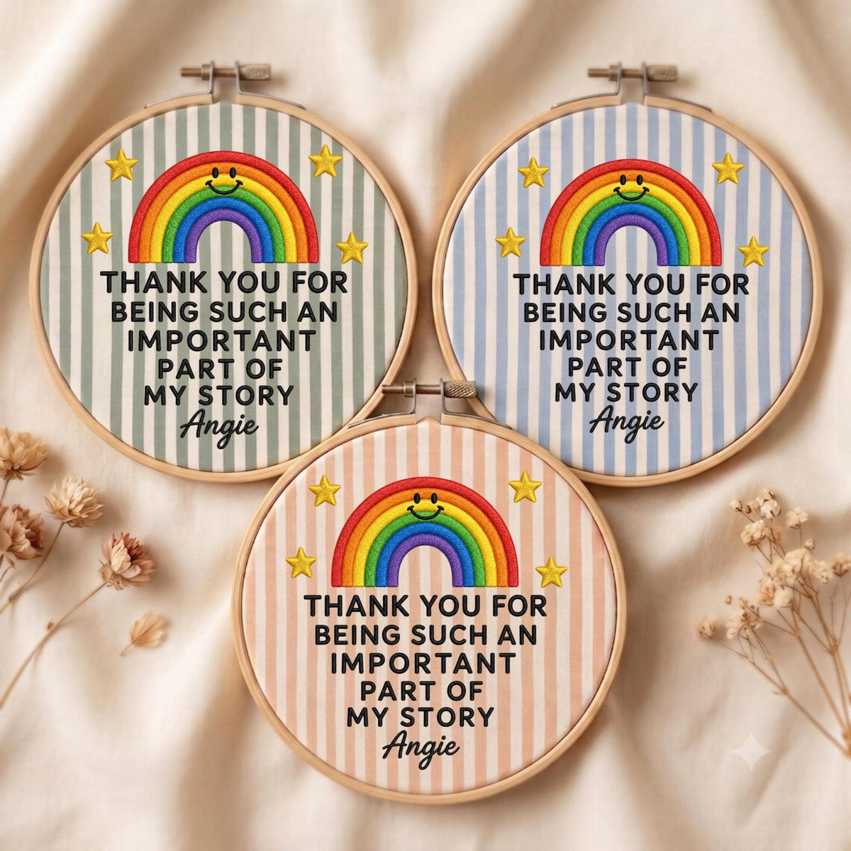 May include: Three circular embroidery hoops featuring striped fabric in sage green, light blue, and peach. Each displays a stitched rainbow with a smiling face, yellow stars, and the text: THANK YOU FOR BEING SUCH AN IMPORTANT PART OF MY STORY Angie.
