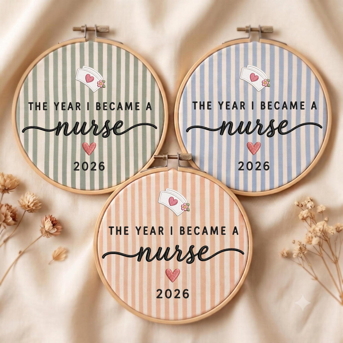 May include: Three circular wooden embroidery hoops featuring striped fabric in sage green, light blue, and peach. Each hoop displays the embroidered text THE YEAR I BECAME A nurse, a small nurse cap icon, a pink heart, and the year 2026.