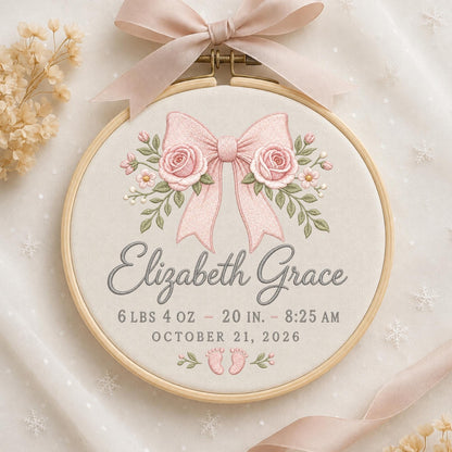 May include: A circular wooden embroidery hoop containing cream fabric with a pink ribbon and rose embroidery. The text reads Elizabeth Grace, 6 lbs 4 oz, 20 in, 8:25 am, October 21, 2026, with small embroidered baby feet at the bottom.