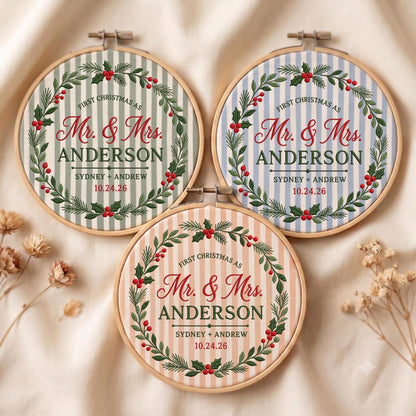 May include: Three circular embroidery hoops featuring fabric with vertical stripes in sage green, light blue, and peach. Each hoop displays a printed Christmas wreath with red berries and green leaves, surrounding the text First Christmas as Mr. &amp; Mrs. ANDERSON, SYDNEY + ANDREW, and 10.24.26.