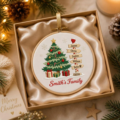 May include: A round embroidery hoop ornament featuring a printed Christmas tree with red and gold ornaments, gifts, and a signpost listing the names James, Olivia, Sophia, William, and Bella with the year 2026 and the text Smith's Family.
