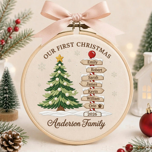 May include: A round wooden embroidery hoop featuring a cream fabric background with an embroidered green Christmas tree, a signpost with names Emily, Robert, Sarah, James, Kevin, William, Orio, the year 2026, and Anderson Family text.