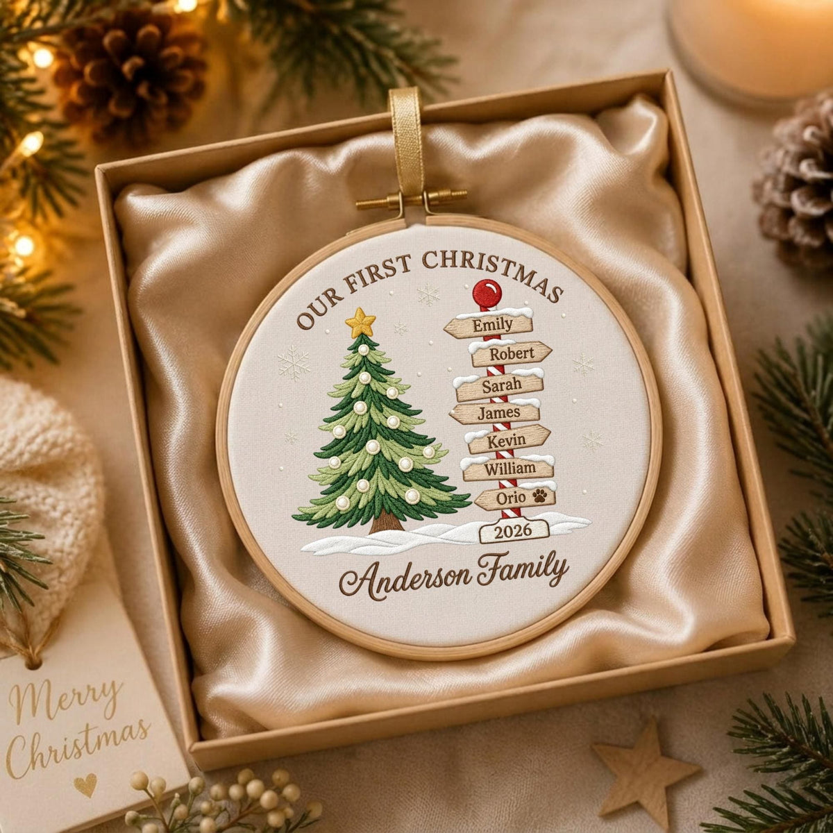 May include: A round embroidery hoop ornament featuring a stitched Christmas tree and a signpost with the names Emily, Robert, Sarah, James, Kevin, William, and Orio, plus the text Our First Christmas, 2026, and Anderson Family.