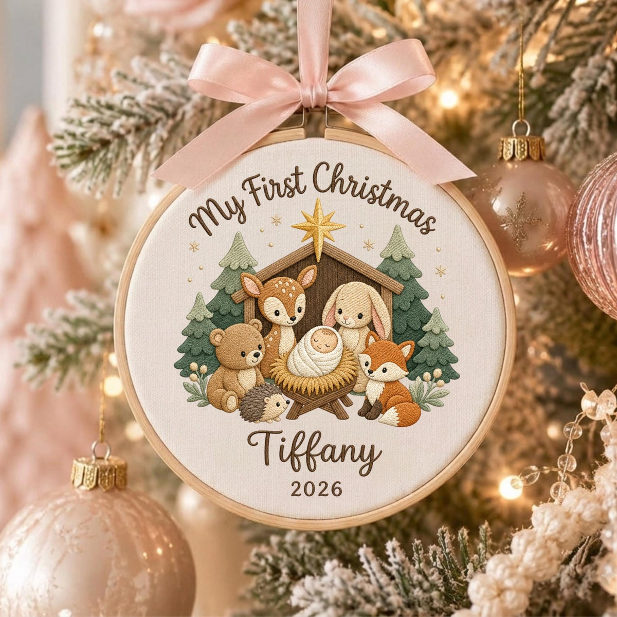 May include: A round wooden embroidery hoop ornament featuring a light fabric center with a printed nativity scene of woodland animals, including a deer, bear, rabbit, fox, and hedgehog. The text reads My First Christmas, Tiffany, and 2026.