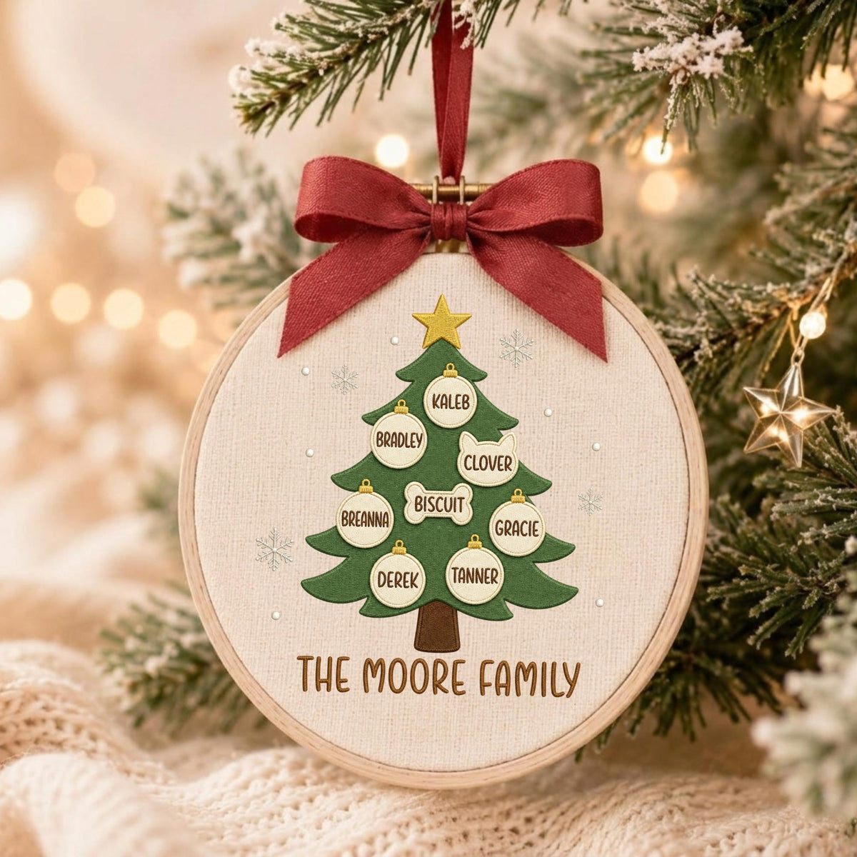 May include: A circular embroidery hoop ornament featuring a green Christmas tree design on cream fabric. The tree is decorated with white ornaments labeled Kaleb, Bradley, Clover, Breanna, Biscuit, Gracie, Derek, Tanner, and The Moore Family text.