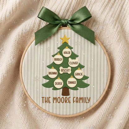 May include: A circular embroidery hoop featuring a green fabric Christmas tree with a yellow star topper. The tree is decorated with white ornaments labeled Kaleb, Bradley, Clover, Biscuit, Breanna, Gracie, Derek, and Tanner. The text reads THE MOORE FAMILY.
