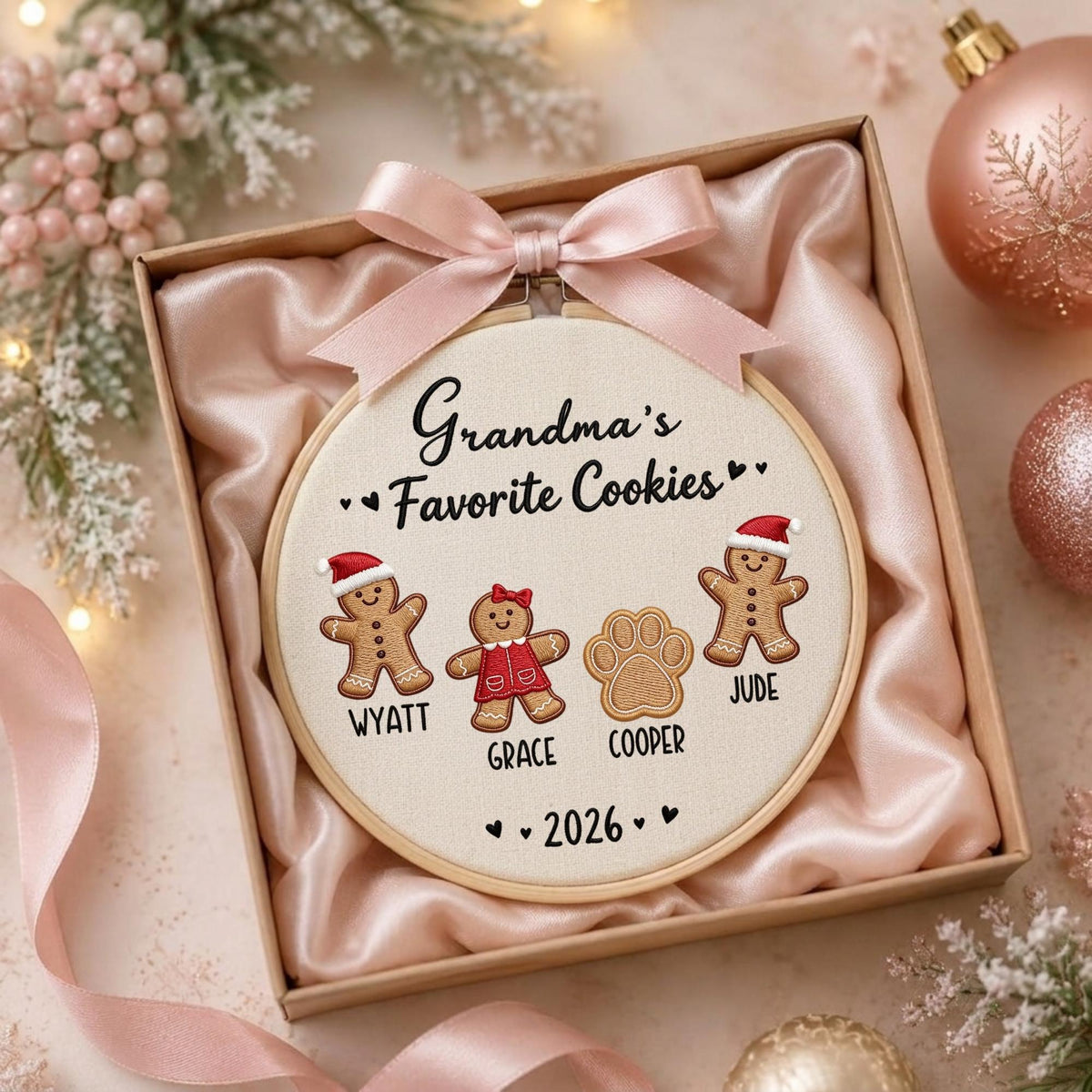 May include: A round embroidery hoop featuring the text Grandma's Favorite Cookies, three gingerbread figures wearing Santa hats or a red dress, and a paw print. Names Wyatt, Grace, and Cooper are stitched below, with the year 2026 at the bottom.