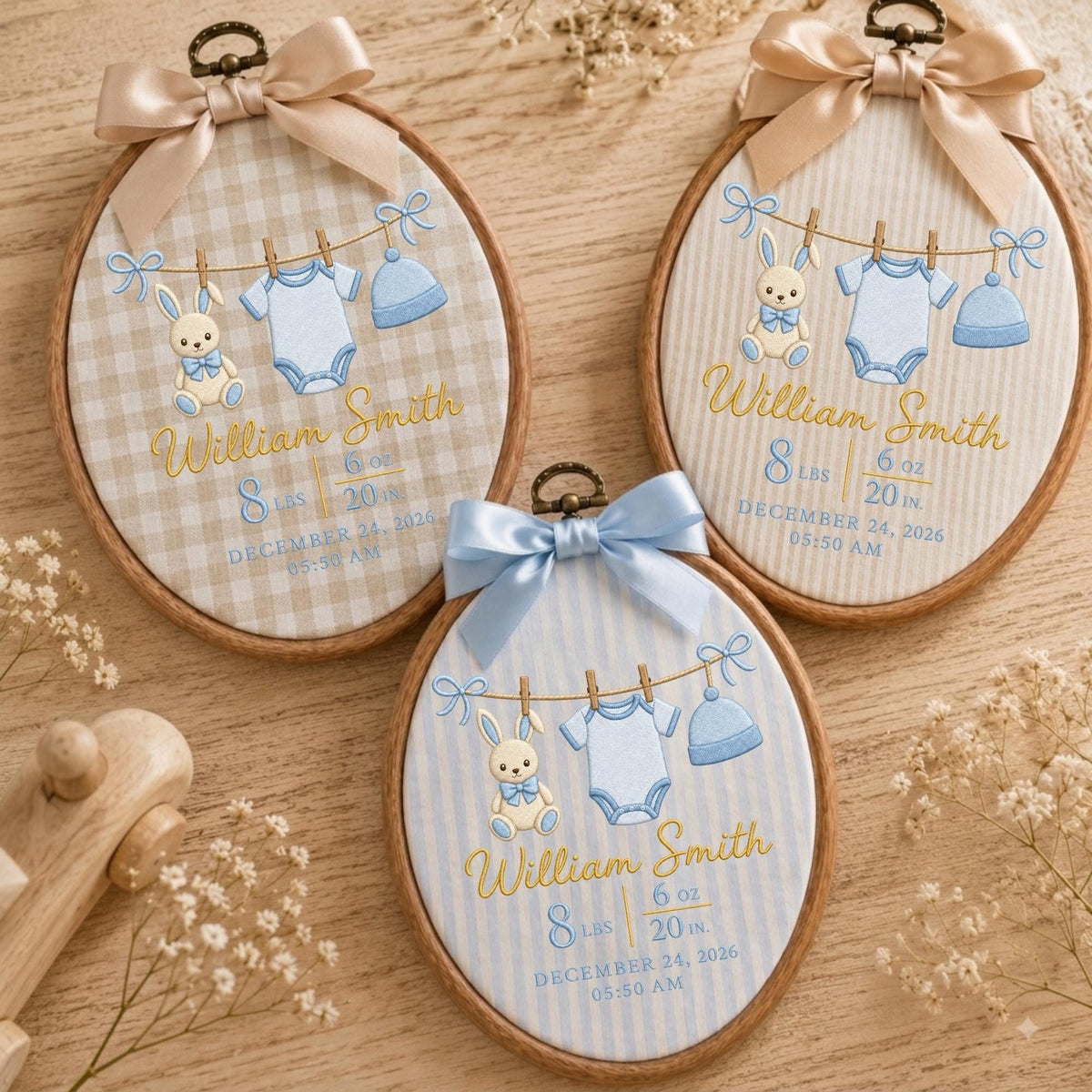 May include: Three oval wooden embroidery hoops featuring personalized baby birth announcements. Each hoop displays a stitched clothesline with a bunny, a onesie, and a hat, plus the name William Smith, 8 lbs, 6 oz, 20 in, and December 24, 2026.
