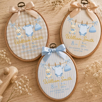 May include: Three oval wooden embroidery hoops featuring personalized baby birth announcements. Each hoop displays a stitched clothesline with a bunny, a onesie, and a hat, plus the name William Smith, 8 lbs, 6 oz, 20 in, and December 24, 2026.