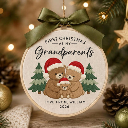 May include: A round embroidery hoop ornament featuring a beige fabric background with the text FIRST CHRISTMAS AS MY Grandparents, a family of three brown teddy bears wearing red Santa hats, two green pine trees, and LOVE FROM, WILLIAM 2026.