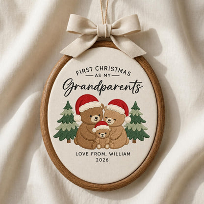 May include: An oval wooden embroidery hoop ornament featuring a cream fabric center with embroidered text FIRST CHRISTMAS AS MY Grandparents, three brown bears wearing red Santa hats, two green pine trees, and the text LOVE FROM, WILLIAM 2026.