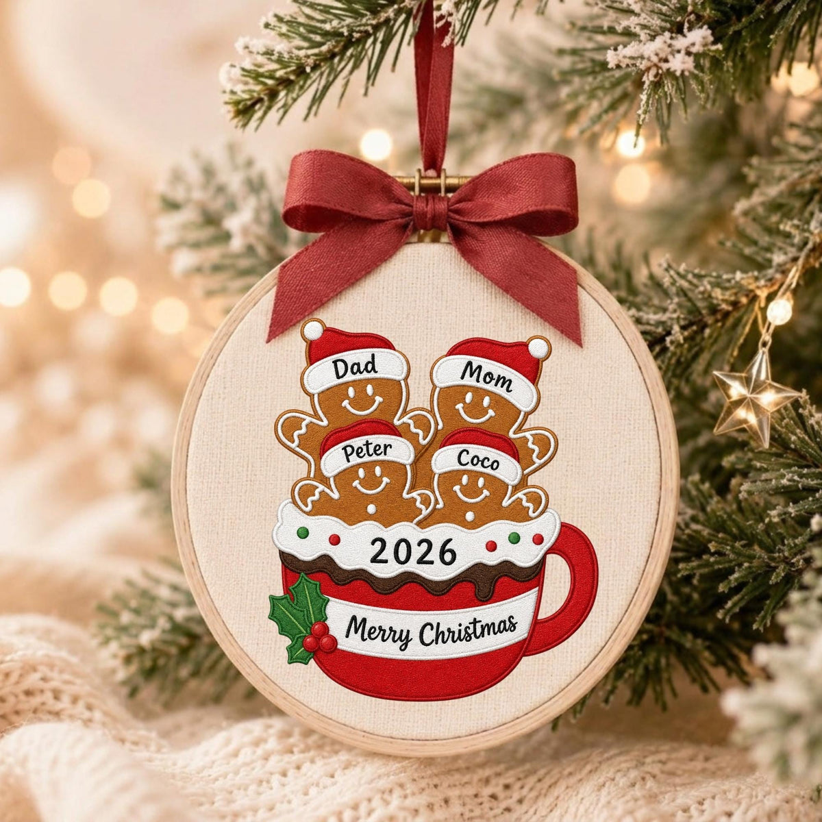 May include: A round embroidery hoop ornament featuring a red mug filled with four gingerbread figures wearing Santa hats labeled Dad, Mom, Peter, and Coco. The mug displays the year 2026 and the text Merry Christmas, topped with a dark red ribbon.
