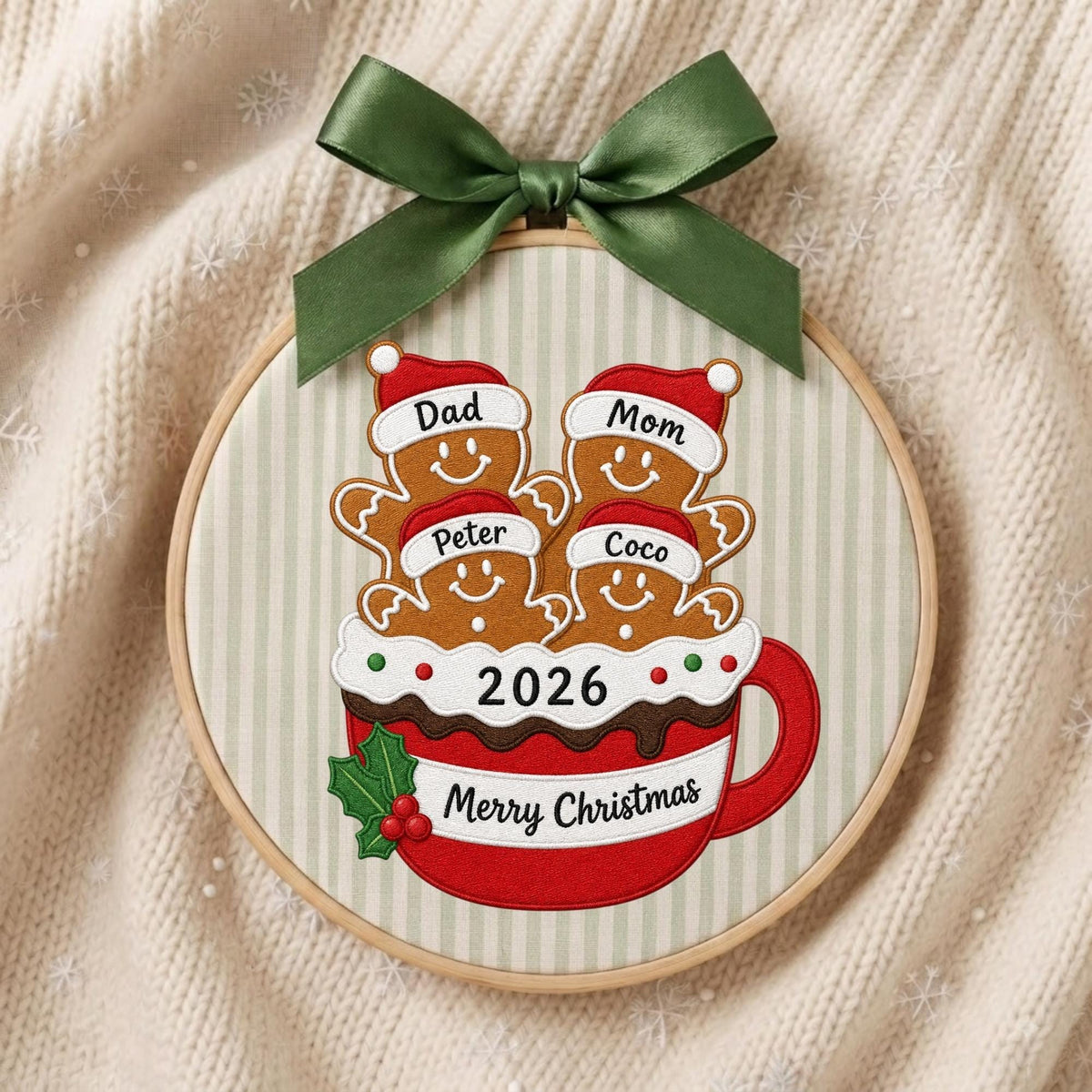 May include: A round embroidery hoop ornament featuring a red mug filled with four gingerbread figures wearing Santa hats labeled Dad, Mom, Peter, and Coco. The mug displays the text 2026 and Merry Christmas, accented by a green satin bow.