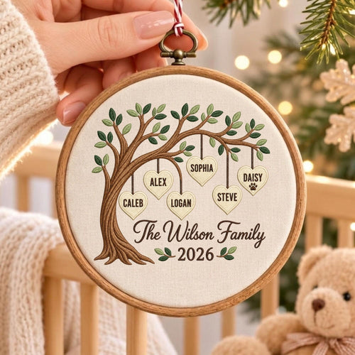 May include: A round wooden embroidery hoop ornament featuring a stitched tree with hanging heart-shaped leaves. The hearts are embroidered with the names Caleb, Alex, Sophia, Logan, Steve, and Daisy. Text reads The Wilson Family 2026.