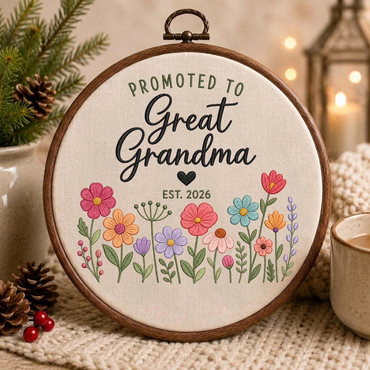 May include: A circular wooden embroidery hoop containing off-white fabric with the embroidered text PROMOTED TO Great Grandma EST. 2026 in black and green. Below the text is a colorful arrangement of embroidered flowers in pink, orange, blue, and purple.