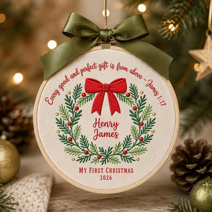 May include: A circular embroidery hoop ornament featuring a cream fabric background with a green embroidered wreath, a red bow, and red text reading Every good and perfect gift is from above ~ James 1:17, Henry James, My First Christmas 2026.