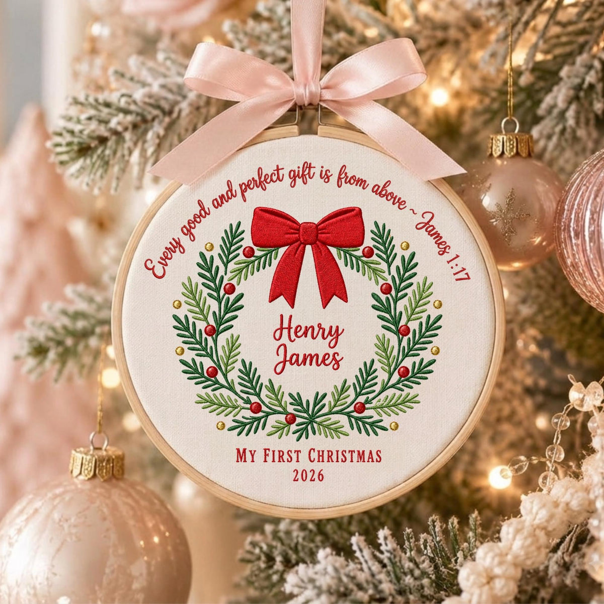 May include: A round wooden embroidery hoop ornament featuring white fabric with an embroidered green wreath, red berries, and a red bow. The text reads: Every good and perfect gift is from above ~ James 1:17, Henry James, My First Christmas 2026.