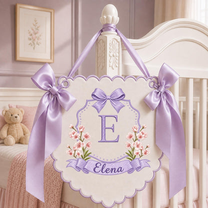 May include: A decorative wall hanging banner featuring a scalloped edge, light purple satin ribbons, and embroidered details. The center displays a large purple letter E, pink floral accents, and a banner with the name Elena in purple script.