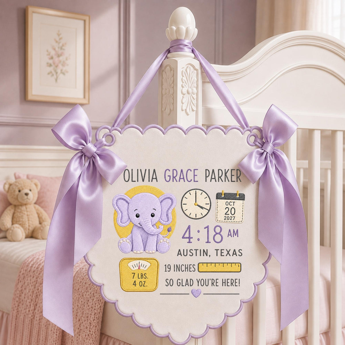 May include: A cream-colored scalloped wall hanging featuring a purple elephant graphic, a clock, a calendar showing Oct 20 2027, and text including Olivia Grace Parker, 4:18 AM, Austin, Texas, 19 inches, 7 lbs. 4 oz., and So Glad You're Here.