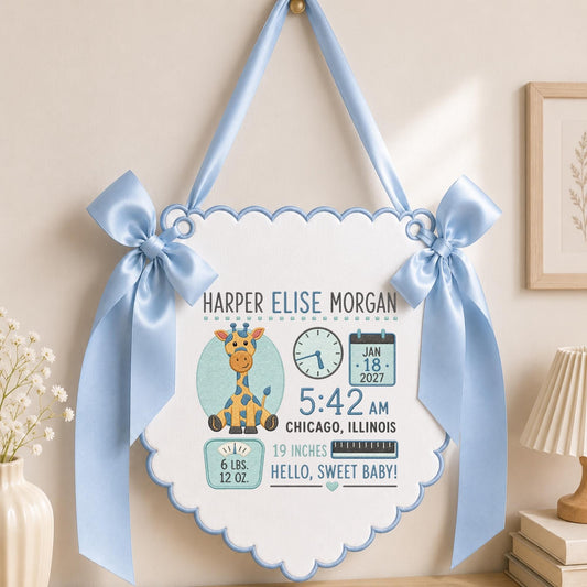 May include: A white scalloped wall hanging with light blue satin ribbon bows and trim. It features a giraffe illustration, a clock, a calendar showing Jan 18, 2027, and text: Harper Elise Morgan, 5:42 AM, Chicago, Illinois, 6 lbs. 12 oz., 19 inches.