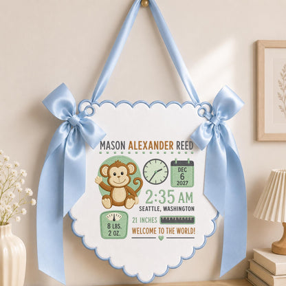 May include: A white scalloped wall hanging with light blue ribbon bows and trim. It features a brown monkey illustration, a clock, a calendar showing Dec 6 2027, and text: Mason Alexander Reed, 2:35 AM, Seattle, Washington, 8 lbs. 2 oz., 21 inches.