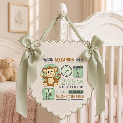 May include: A cream-colored fabric wall hanging with scalloped edges and sage green satin ribbons. It features an embroidered brown monkey, a clock showing 2:35 AM, a calendar for Dec 6 2027, a scale reading 8 lbs. 2 oz., and the text Mason Alexander Reed.